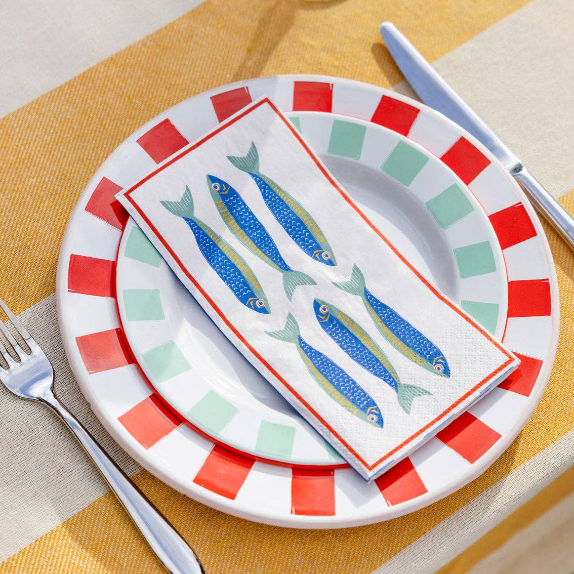 Servietter med sardinmotiv brettet på dekket sommerbord