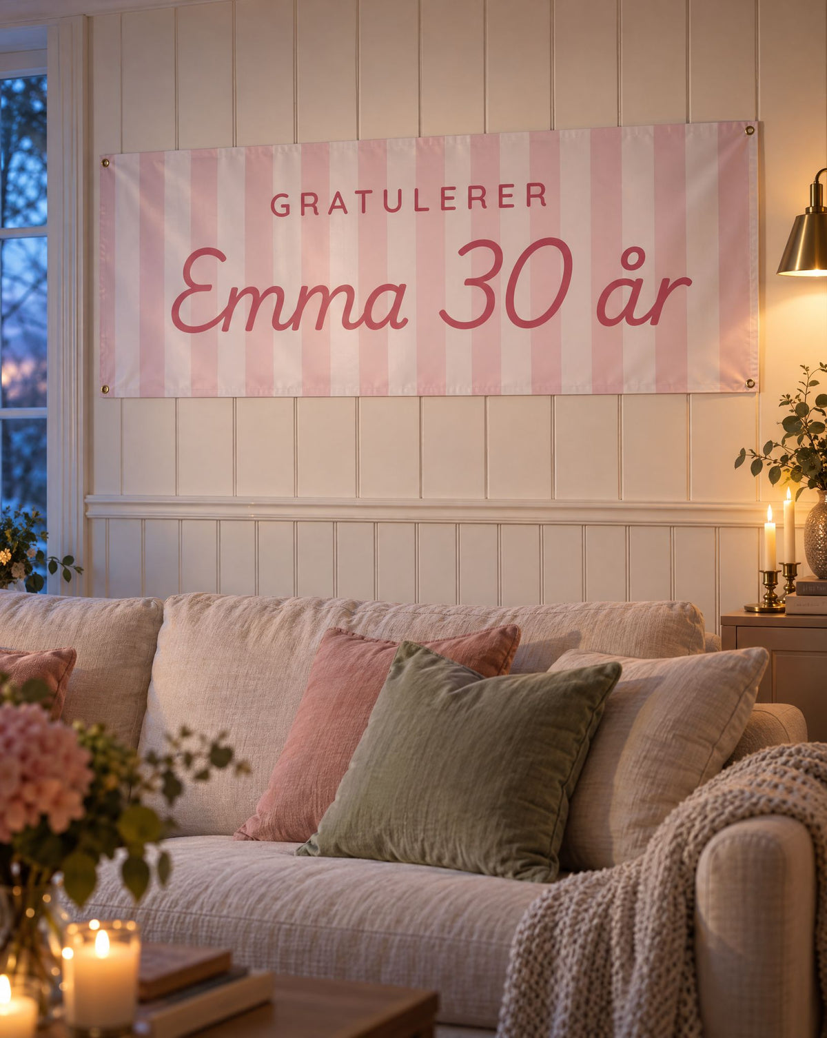 Rosa pastellstripebanner med Gratulerer Emma 30 år på veggen over sofaen i en lun stue